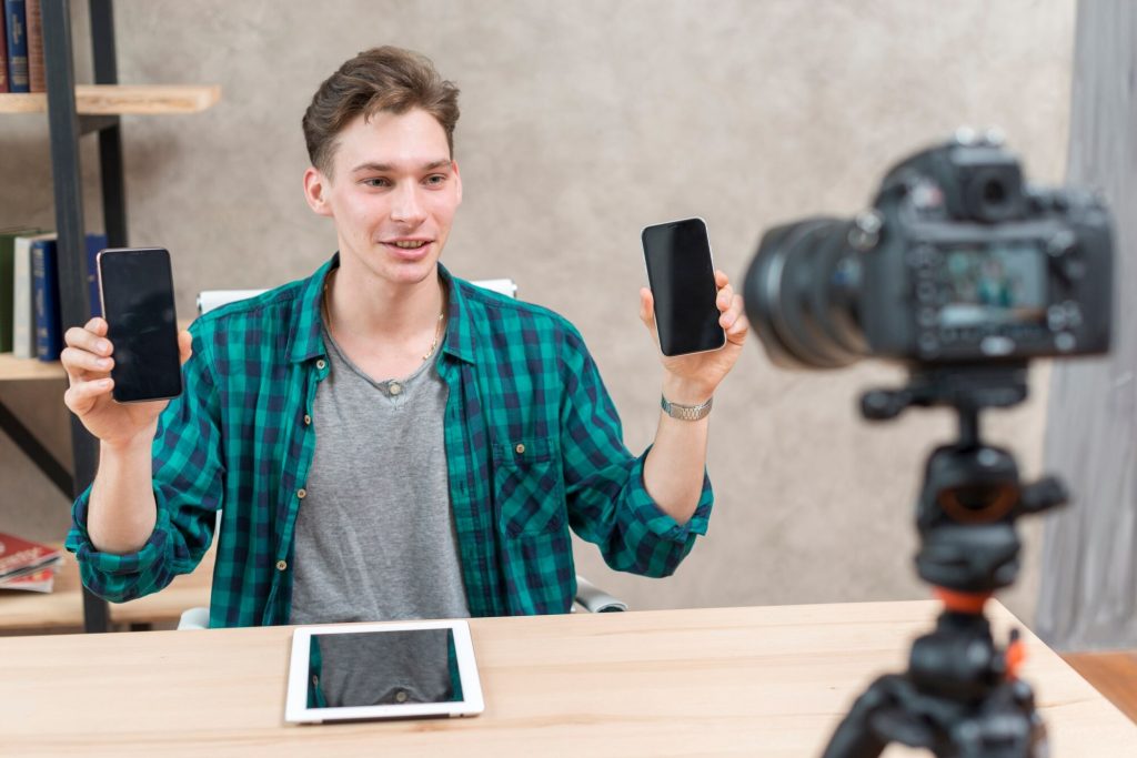 Man holding two smartphones while filming a tech video.